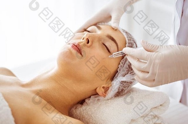 美容师美过程注射器脸年轻的浅黑肤色的女人女人化妆品医学手术美注射