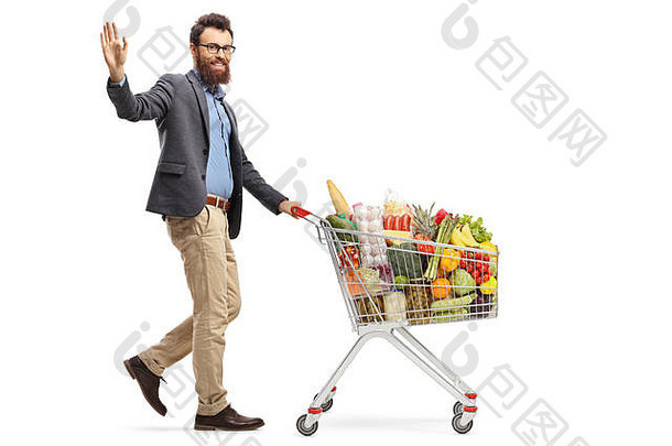 完整的长度拍摄男人。走购物车食物产品挥舞着手孤立的白色背景