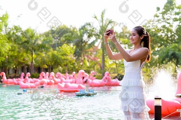 快乐年轻的美丽的亚洲女人采取图片电话在户外