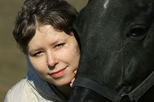 肖像有吸引力的女孩拥抱黑色的马