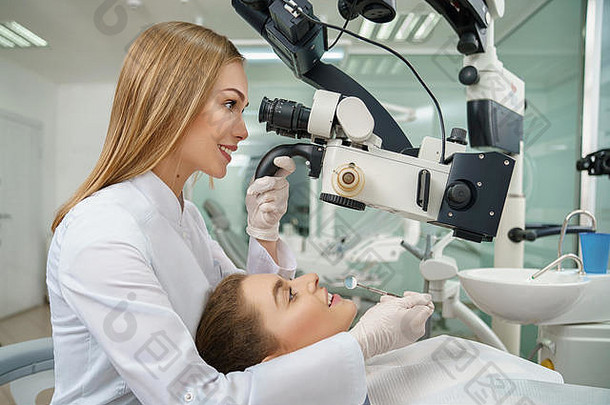 女牙医检查牙齿病人专业牙科显微镜美丽<strong>的</strong>金发女郎女人微笑现代显微镜病人说谎牙医椅子