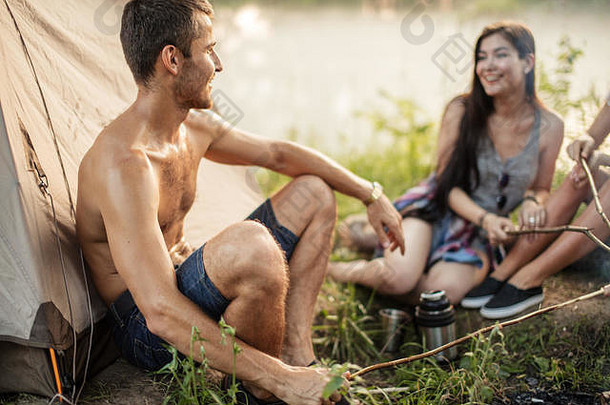 愉快的男人。欣赏美女孩坐着草