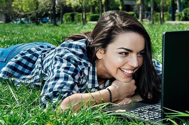 女人休息草坪上移动PC