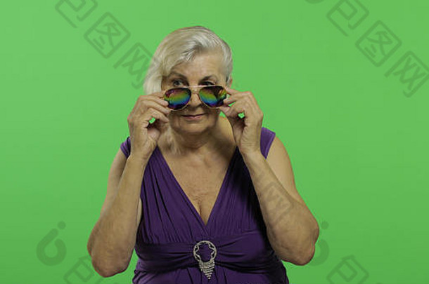 上了年纪的女人太阳镜微笑漂亮的快乐祖母紫色的衣服的地方标志文本浓度关键绿色屏幕背景