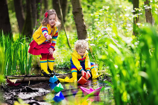 孩子们玩色彩斑斓的纸船小河阳光明媚的春天一天孩子们玩探索自然