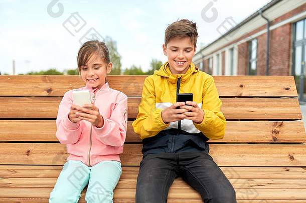 孩子们智能手机坐着街板凳上