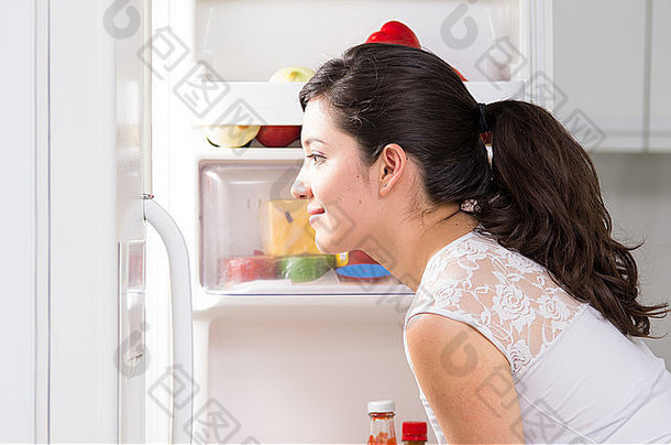 年轻的美丽的女人搜索食物冰箱