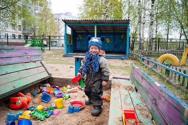 男孩年很酷的春天阳光明媚的一天玩沙盒幼儿园显示各种情绪玩具春天凉爽温暖的衣服