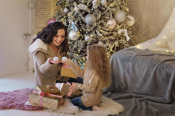 家庭庆祝<strong>活动</strong>妈妈。女儿坐着圣诞节树持<strong>有礼</strong>物球装饰快乐童年
