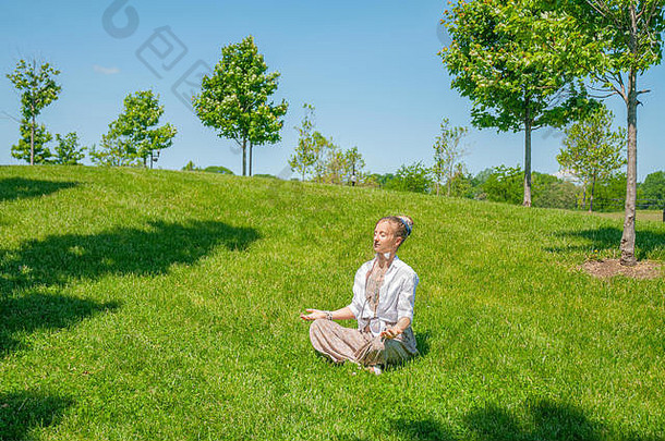 美丽的放荡不羁的风格女人配件享受夏天阳光明媚的一天公园波西米亚嬉皮女孩冥想坐着莲花构成草