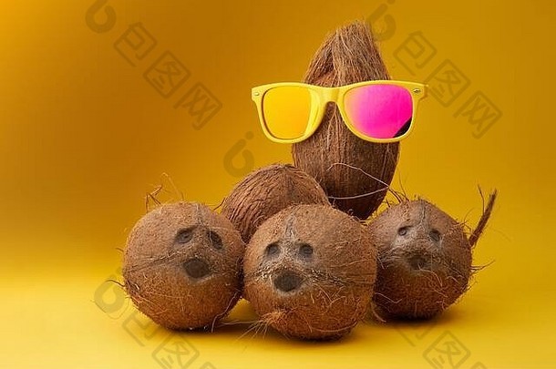 集团有趣的椰子黄色的背景椰子穿太阳镜概念站人群夏天