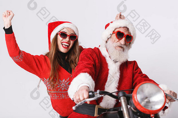 圣诞老人老人白色胡子穿sungasses年轻的夫人老人穿圣诞老人他红色的毛衣太阳镜微笑骑摩托车一年圣诞节假期记忆礼物购物折扣商店雪少女圣诞老人老人化妆发型狂欢节