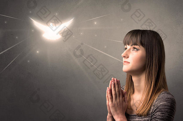 年轻的女人祈祷灰色背景闪闪发光的鸟