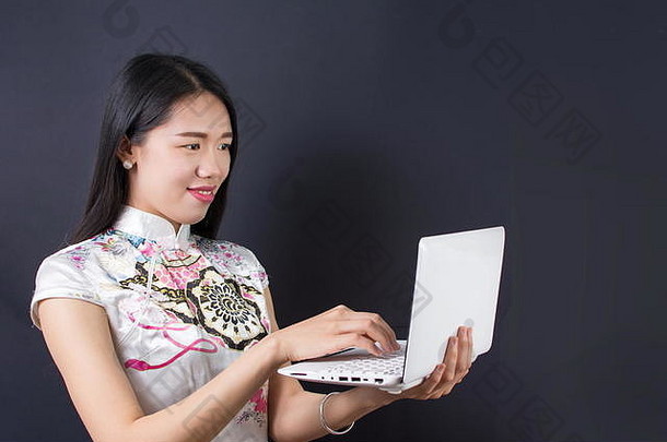 年轻的亚洲女人持有移动PC穿中国人衣服