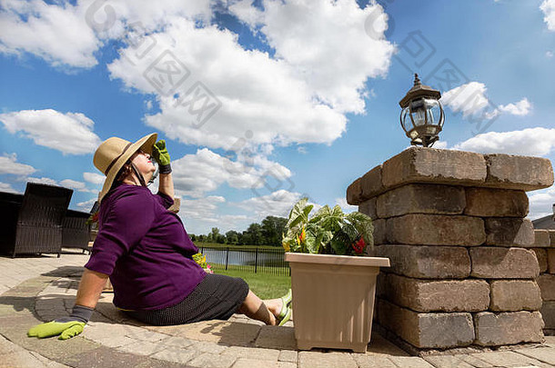 活跃的退休夫人采取打破园艺放松一步天井头倾斜的回来太阳享受