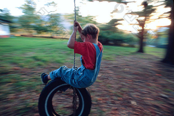 男孩波动坐着轮胎系绳子