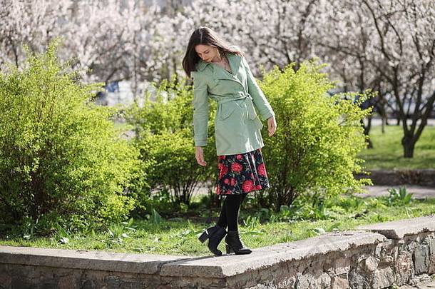 年轻的女人摆姿势绿色灌木开花杏背景
