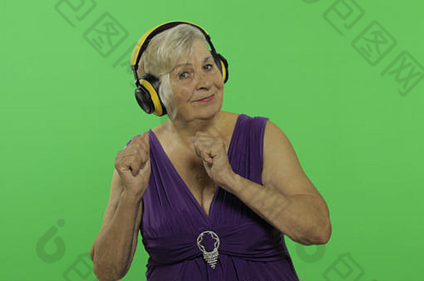 上了年纪的女人听音乐耳机舞蹈漂亮的祖母紫色的衣服的地方标志文本浓度关键绿色屏幕背景