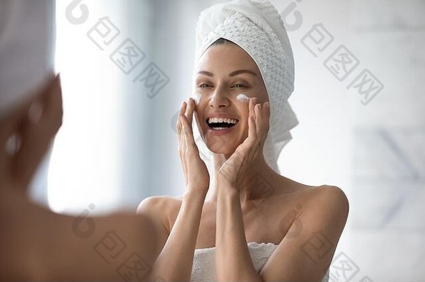女人触摸脸应用有爱心的皮肤保湿霜奶油
