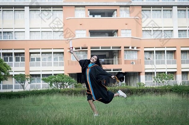 肖像快乐兴奋年轻的亚洲女大学研究生穿毕业礼服他庆祝学位大学校园