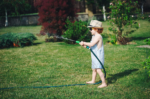 可爱的男孩浇水花园软管
