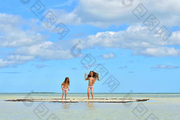 孩子们玩沙滩海洋可爱的女孩桑迪海滩日落光古巴卡亚椰子树