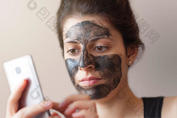 年轻的浅黑肤色的女人意大利女孩黑色的美面具脸检查电话自然光未来窗口一边