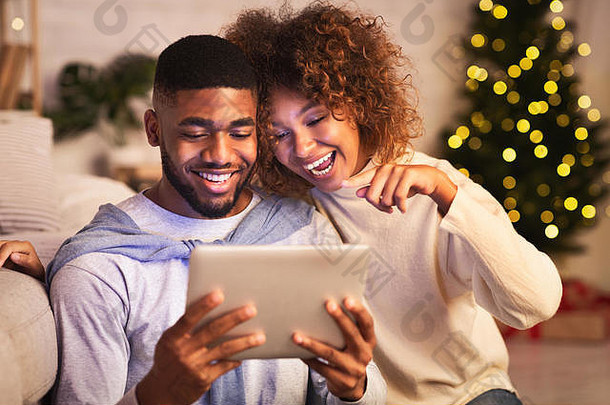 快乐非洲式发型夫妇选择电影平板电脑享受舒适的晚上