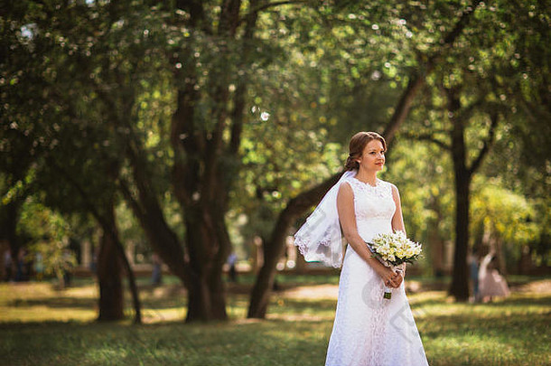 肖像年轻的新娘婚礼花束公园背景