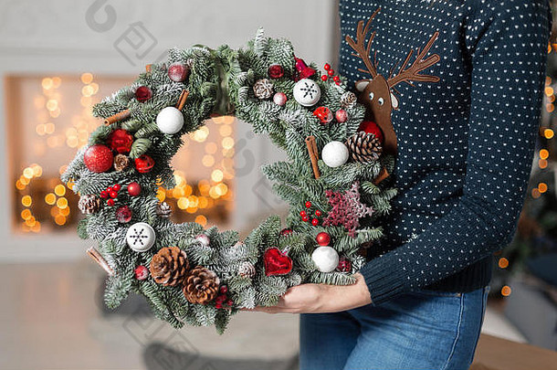 年轻的女人持有圣诞节花环冷杉分支机构假期一年庆祝活动背景壁炉圣诞节树灯花环