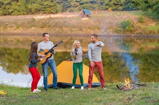 集团快乐朋友吉他有趣的户外跳舞跳湖公园背景美丽的天空野营有趣的