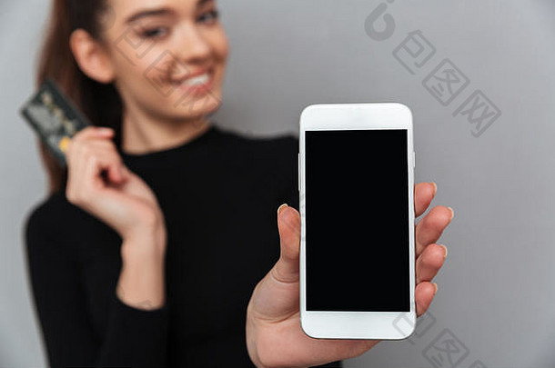 微笑浅黑肤色的女人女人黑色的衣服持有信贷卡显示空白智能手机屏幕相机焦点电话
