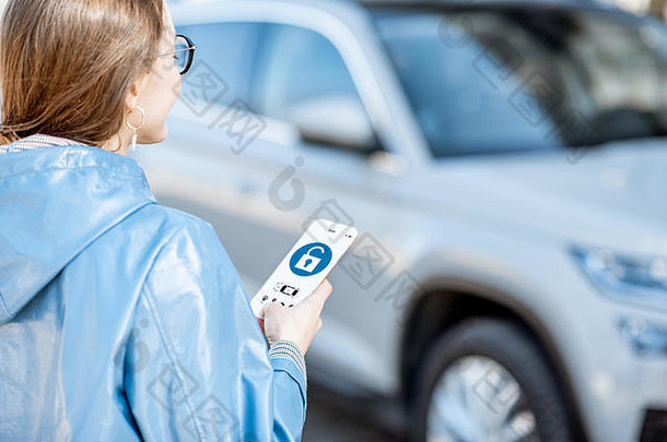 女人解锁车移动应用程序聪明的电话概念远程控制车保护互联网
