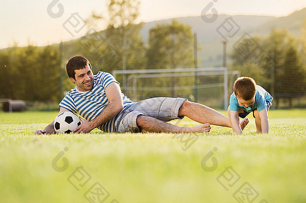 年轻的父亲儿子玩足球足球球场