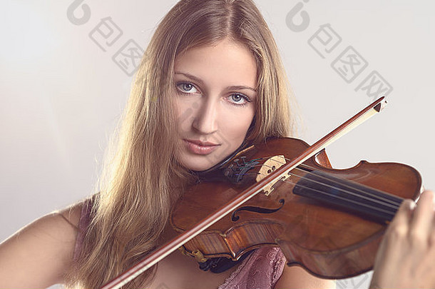 漂亮的年轻的女小提琴家时尚的粉红色的装站玩小提琴<strong>经典</strong>独奏会学院