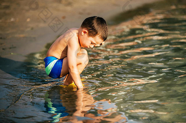 可爱的男孩玩有趣的水海滩孩子家庭概念