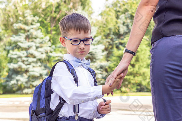 男孩一年级眼镜蓝色的公文包持有妈妈。手