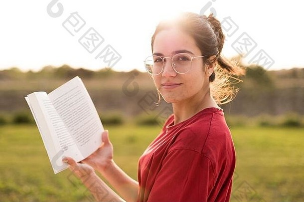 年轻的女人不错的阅读微笑享受光日落公园