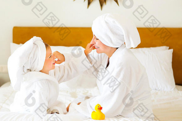 快乐妈妈。女儿浴袍奶油面具家庭护理水疗中心概念