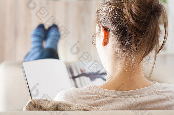 年轻的女人阅读杂志书放松沙发