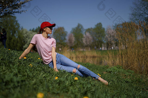 成功的业务女人享受休闲免费的时间公园开花樱花樱桃树穿牛仔裤粉红色的t恤时尚红色的帽
