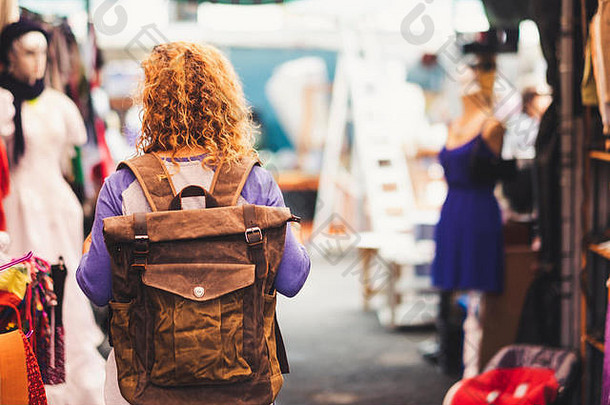 金发女郎卷曲的头发女人背包客旅行者查看后市场享受购物替代假期皮革背包视图