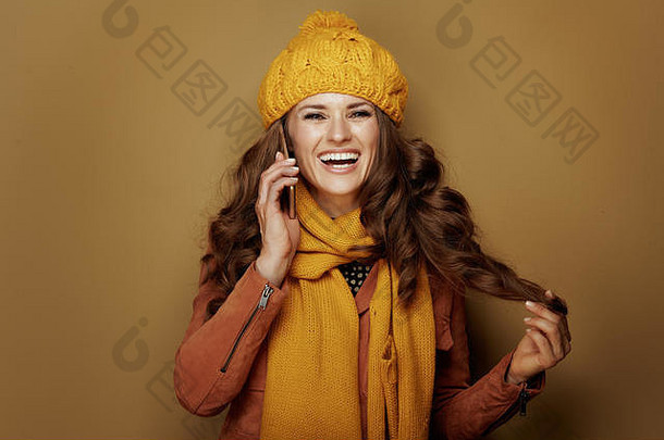 肖像微笑现代女人黄色的贝雷帽围巾智能手机青铜背景