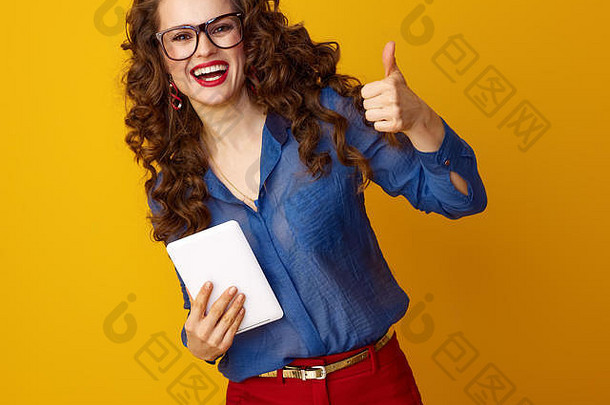 快乐时尚的女人长波浪浅黑肤色的女人头发平板电脑显示拇指孤立的黄色的背景