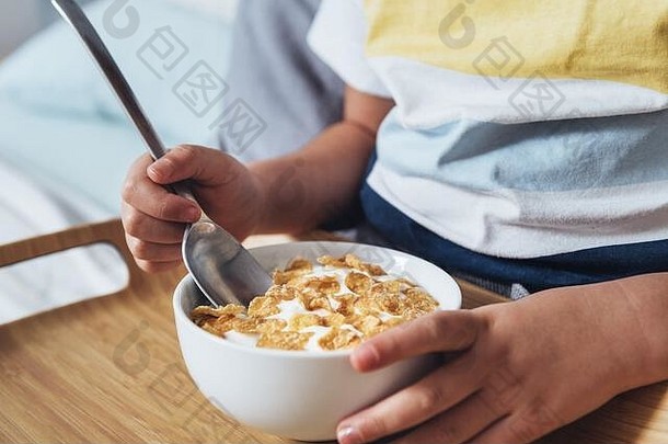 细节女孩坐着床上持有勺子碗麦片牛奶早餐孩子享受健康的食物健康的
