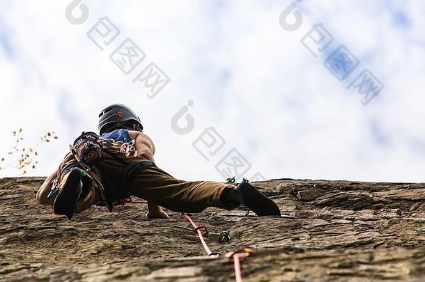 低角视图岩石登山者行动穿工具包带拴牢设备安全夹攀爬高锯齿状的石头复制空间