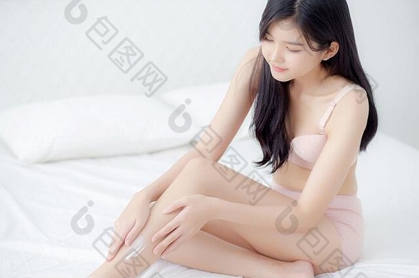美丽的年轻的亚洲女人触摸皮肤腿光滑的奶油乳液水合作用光滑的女孩应用身体护理化妆品柔滑的