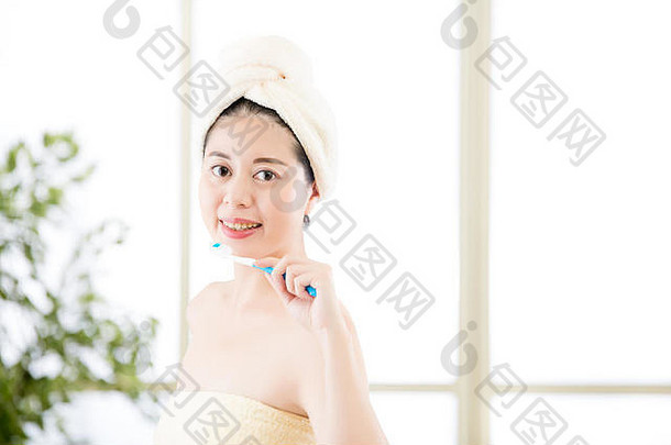 微笑亚洲女人干燥毛巾头持有牙刷美健康概念在室内背景