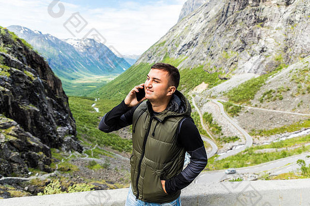 照片英俊的快乐年轻的男人。免费的替代假期野营会说话的移动电话