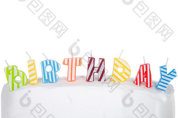 色彩斑斓的条纹蜡烛形成词生日白色磨砂蛋糕孤立的白色背景